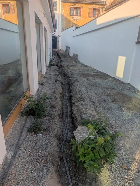 Výkop pro rozvody podél fasády ve dvoře